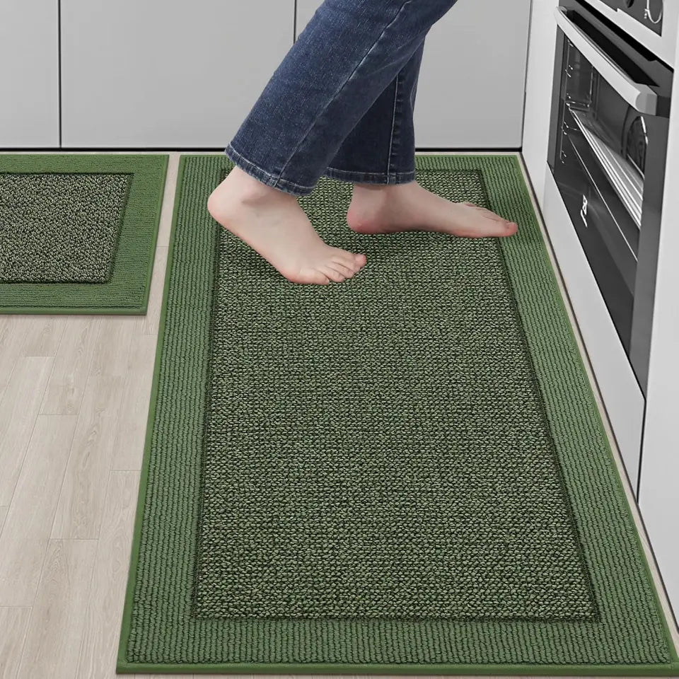 Green kitchen mat on a wooden floor with a person wearing jeans and bare feet stepping onto it.