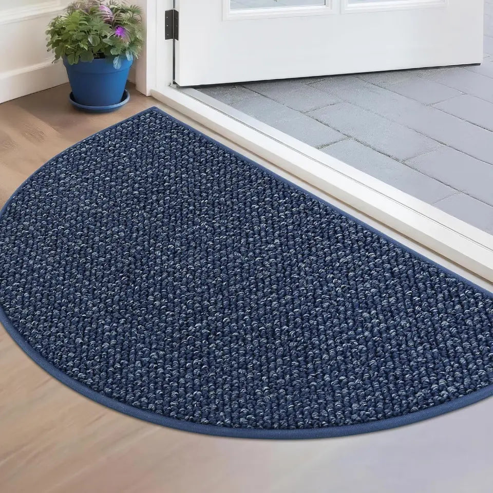 Blue doormat on a wooden floor with a plant in the background