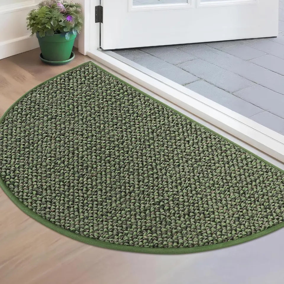Green doormat on a wooden floor with a white door in the background
