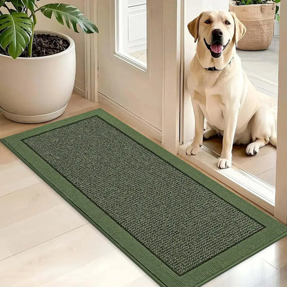 Green doormat on a wooden floor with a dog sitting inside a house.