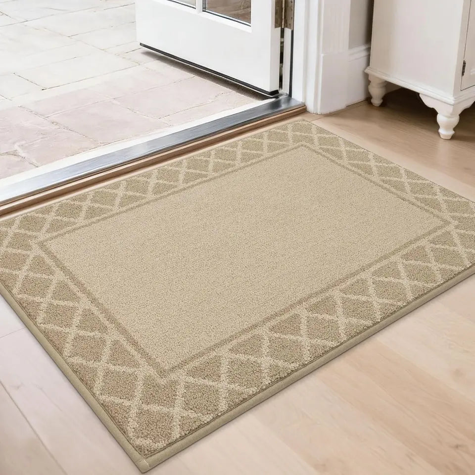 Beige doormat with geometric pattern on a wooden floor in front of a white door.