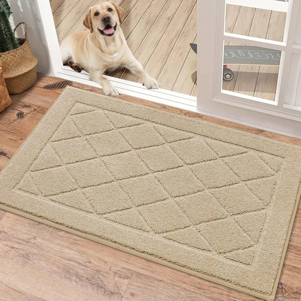 Beige doormat with diamond pattern on a wooden floor, dog looking through a glass door in the background.